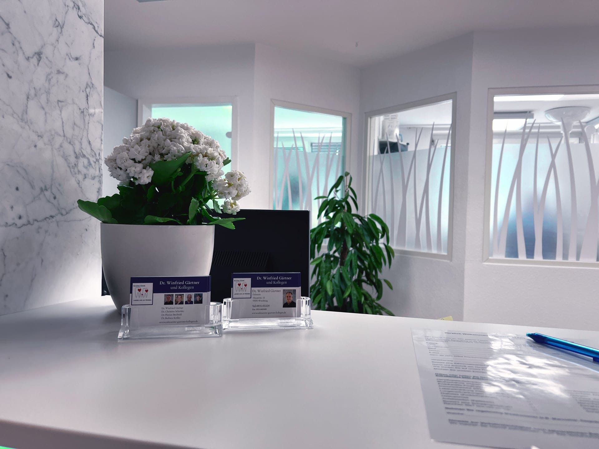 Theke mit Visitenkarten der Praxis und wei&szlig;er Blume